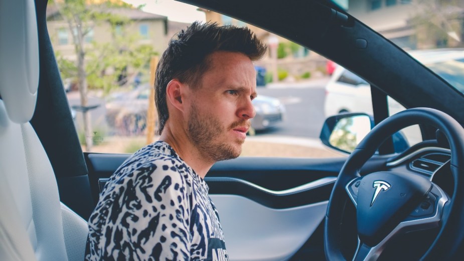 Man with serious face driving a Tesla, highlighting what to do if you have to go pee while driving a car