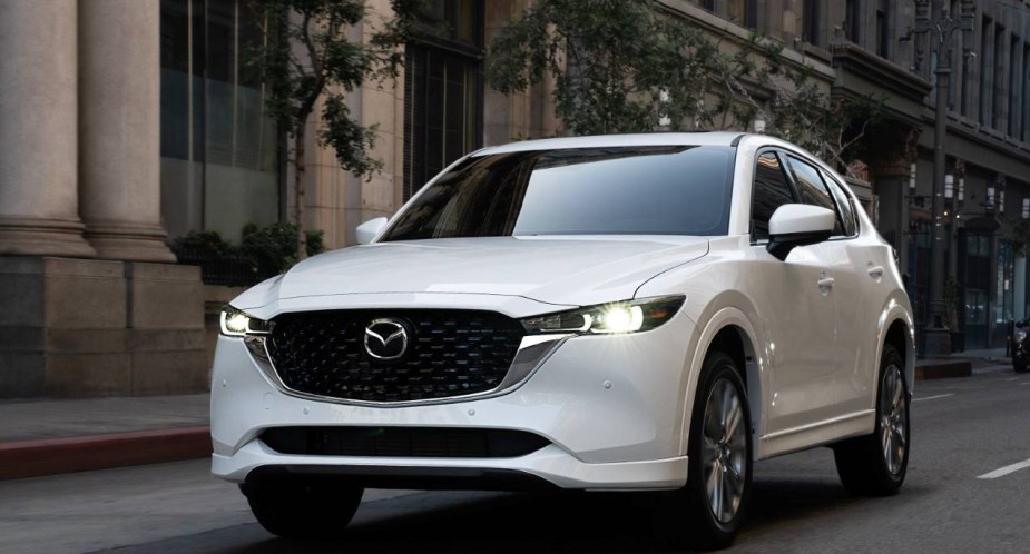 A white Mazda CX-5 compact SUV is driving on the road. 