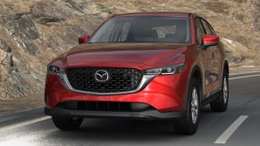 A red 2022 Mazda CX-5 small SUV is driving down the road.