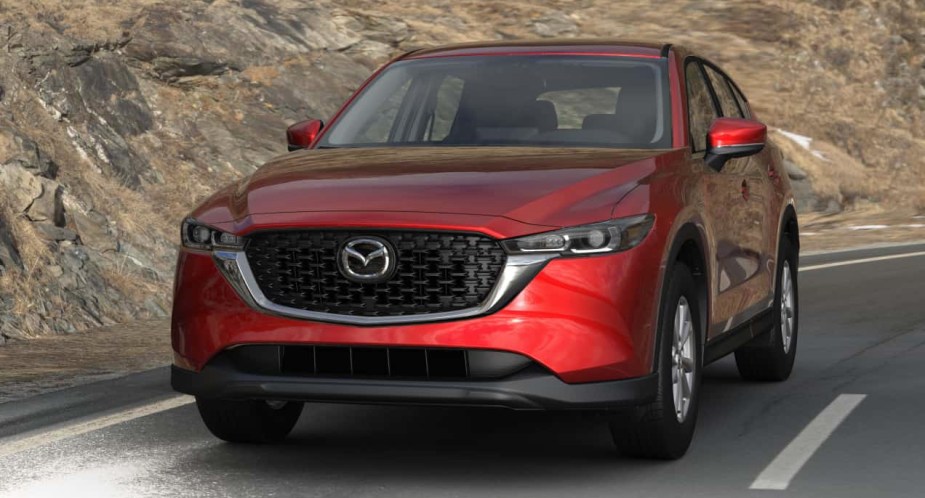 A red 2022 Mazda CX-5 compact SUV is driving on the road. 