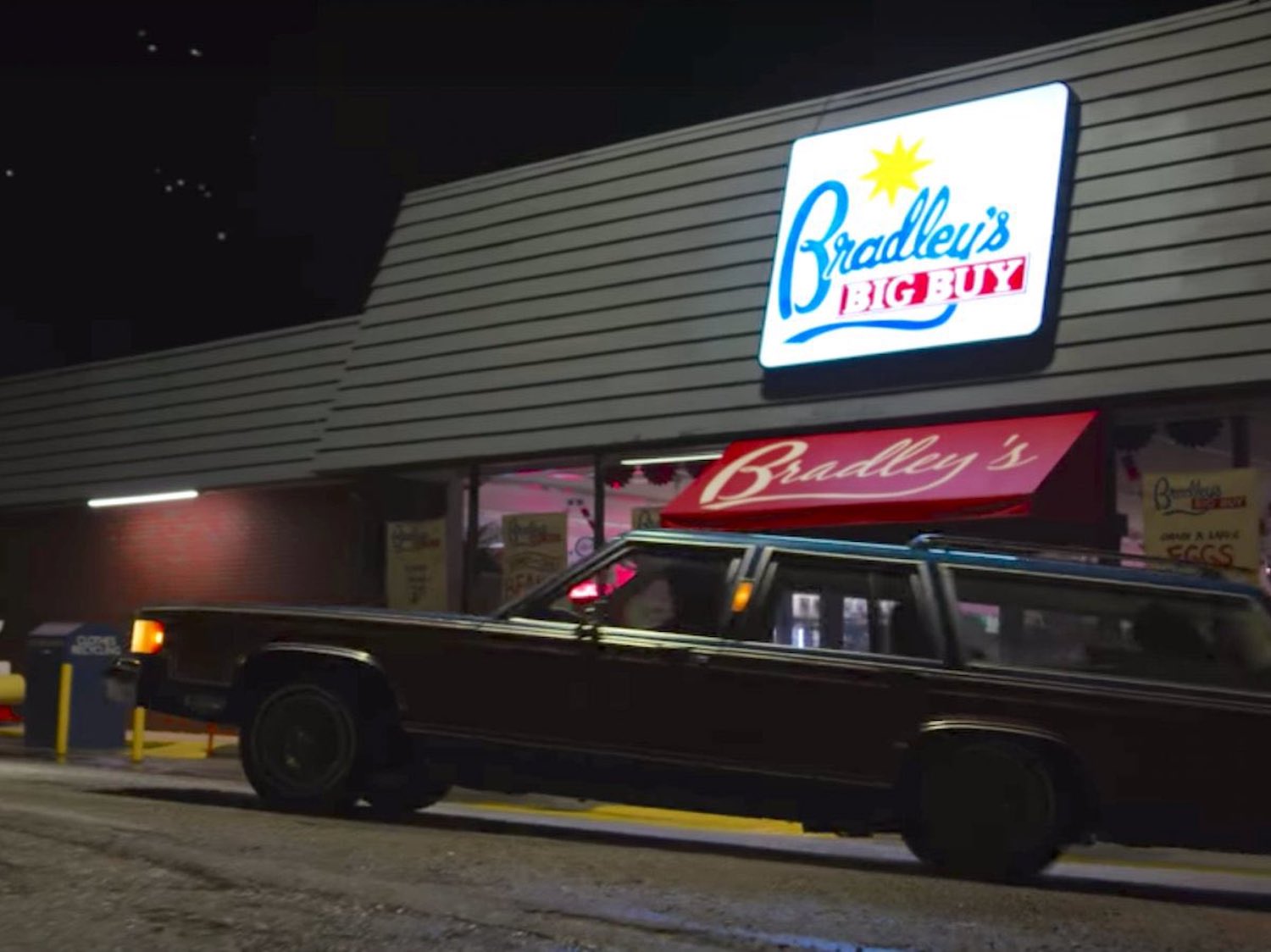A Mercury Station Wagon turning around on a street at night, a grocery store visible in the background.