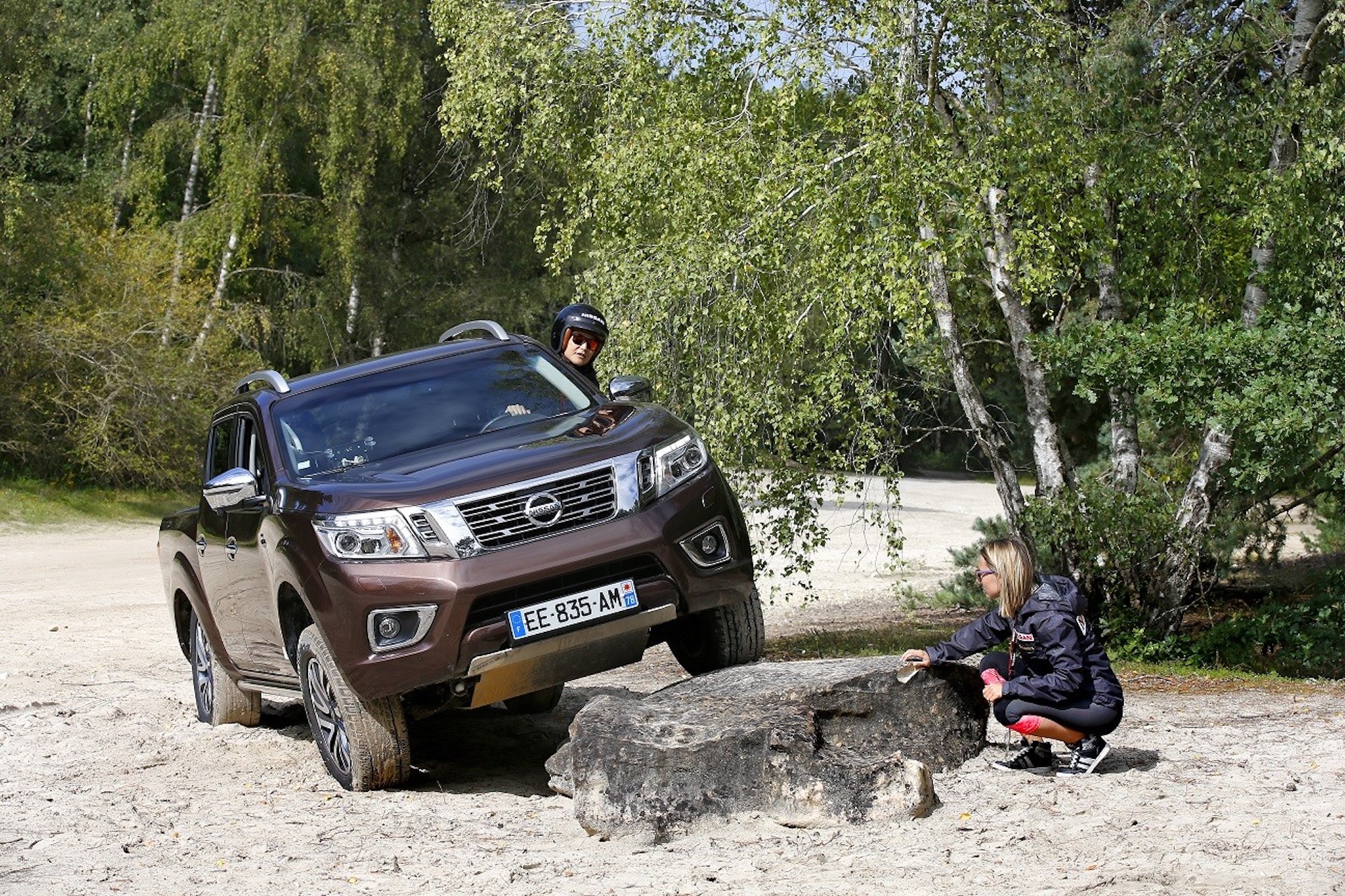 A burgundy colored Nissan Navara-R driving over a rock.