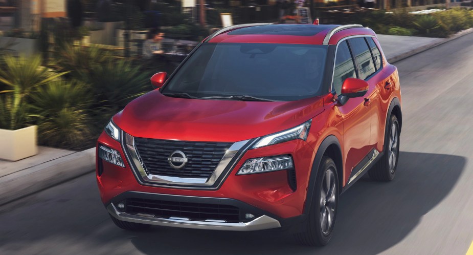 A red 2022 Nissan Rogue is driving on the road. 