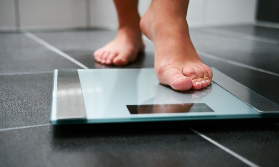 Person Stepping on a Bathroom Scale - Gravity Working Against Us