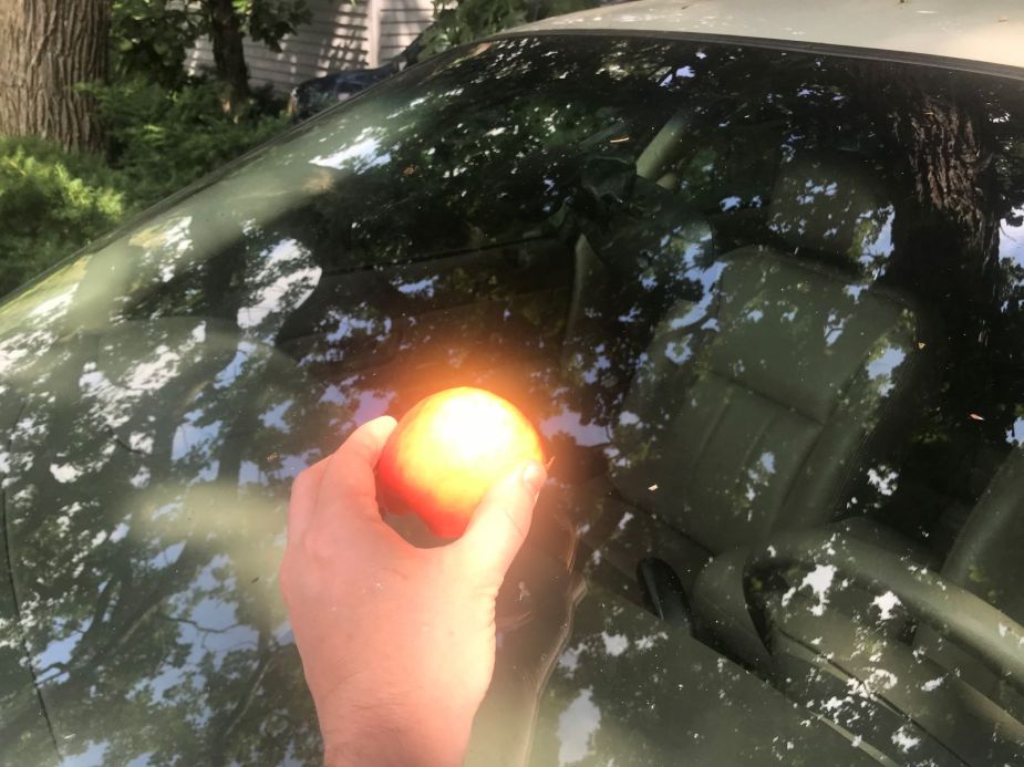 Person rubbing an apple on a car windshield, highlighting the secret apple trick for a windshield