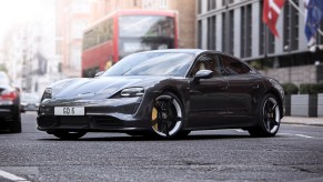 A dark colored Porsche Taycan parked in an outdoor city environment.