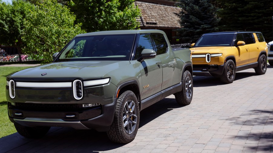 Rivian R1T parked in front of a yellow Rivian SUV