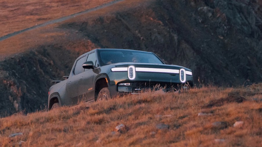 A green 2022 Rivian R1T is on a hill.