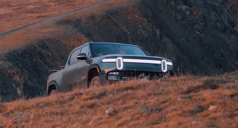 A green 2022 Rivian R1T is parked on a hill. 