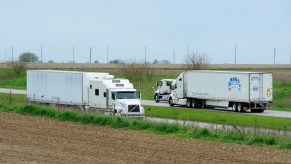 Semi-trucks and their different semi-truck trailers driving down the road.