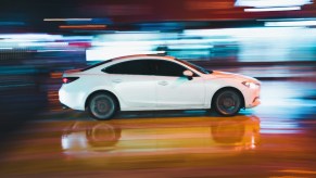 Side view of white car speeding, highlighting ISA anti-speeding technology mandatory for new cars in Europe