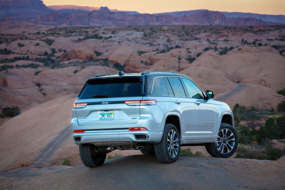 Silver 2023 Jeep Grand Cherokee parked on a hill, highlights its release date and price