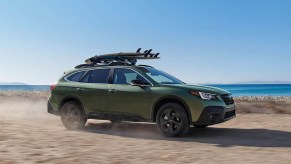A pale green 2022 Subaru Outback driving on the beach.
