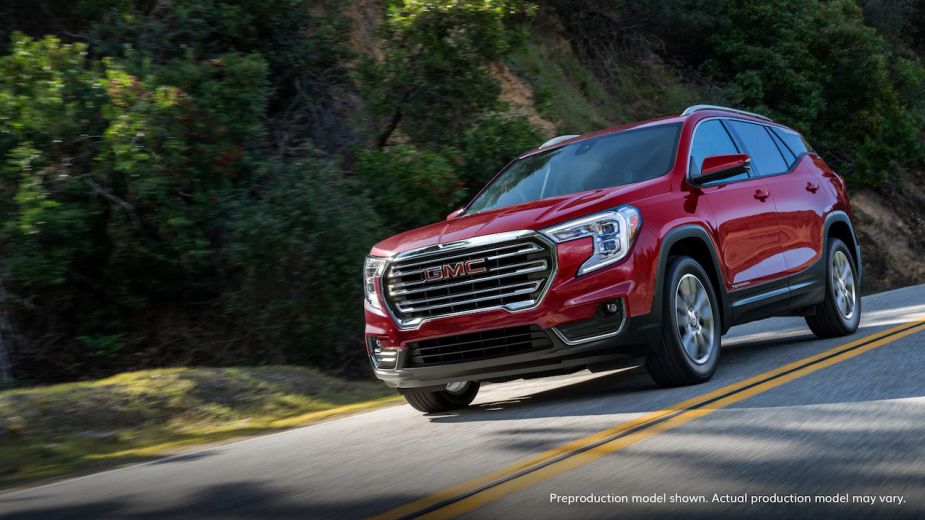 A red 2022 GMC Terrain driving on the road. Is the SLE or SLT trim levels the better choice?