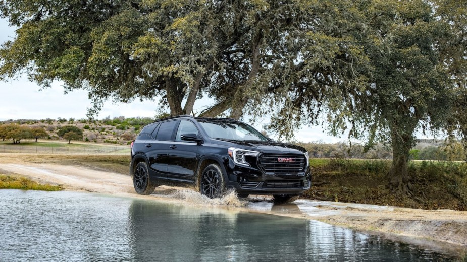 A black 2022 GMC Terrain driving. Is the SLE or SLT trim better? Why do GM buyers have to pay $1,500 for an OnStar Subscription?