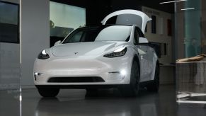 A white Tesla Model Y compact electric SUV with its trunk open on display at a shopping mall in Culver City, California