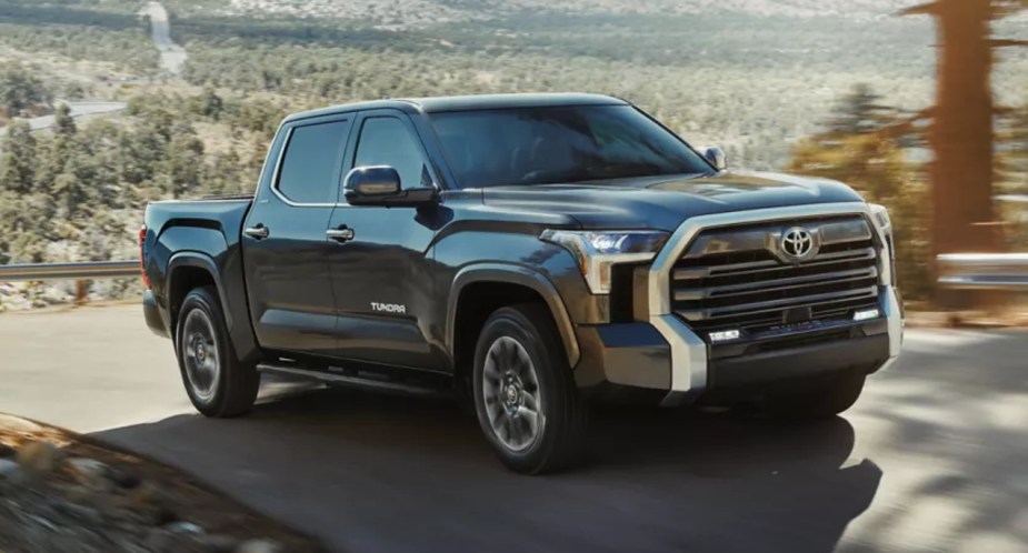 A black 2022 Toyota Tundra full-size pickup truck is driving on the road. 