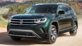 A green 2022 Volkswagen Atlas midsize SUV is driving off-road.