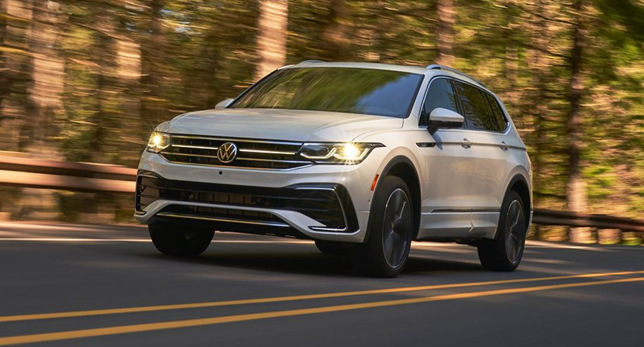 A white 2022 Volkswagen Tiguan R-Line compact SUV is driving on the road.