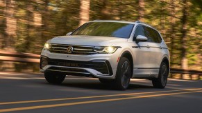 A white 2022 Volkswagen Tiguan R-Line compact SUV is driving on the road.