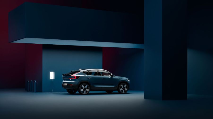 A Volvo C40 Recharge electric SUV model in Fjord Blue charging in a darkened room