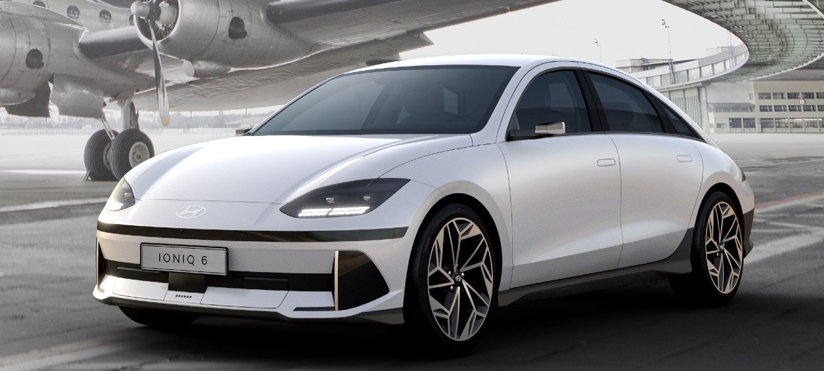 White 2024 Hyundai IONIQ 6 electric sedan parked near an airplane, highlighting its release date and price