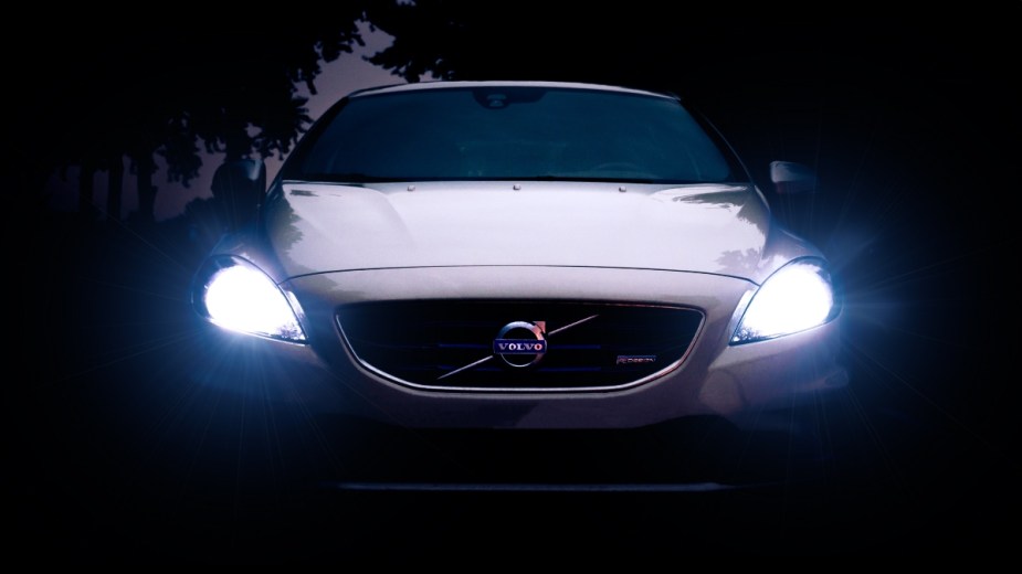 White Volvo car with shining headlights, highlighting reasons why car have two headlights instead of one
