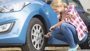 Woman Checking Tire Pressure, this is an easy car maintenance item