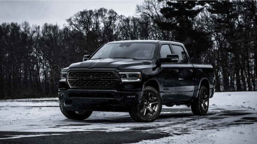 A black 2022 Ram 1500 full-size pickup truck parked on grass covered snow near barren trees