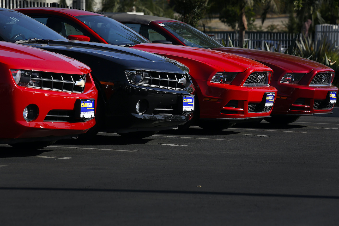 Used Chevrolet Camaros and Ford Mustangs are displayed for sale at a CarMax.