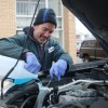 A mechanic pours coolant into a car