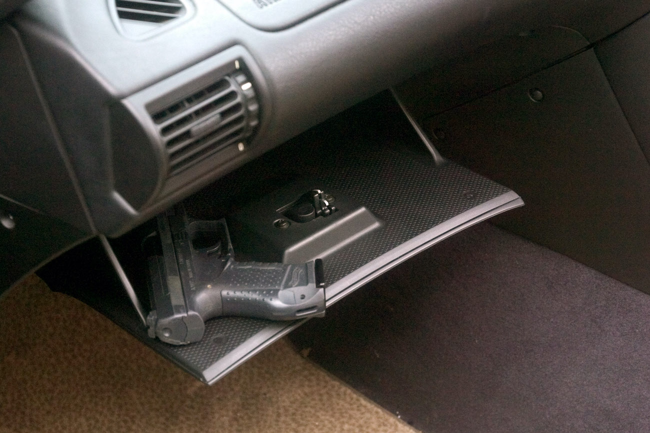 A hand gun in the glove compartment of a car.