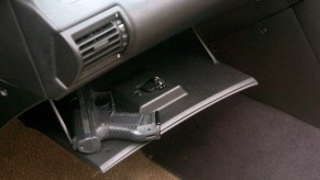 A hand gun in the glove compartment of a car.