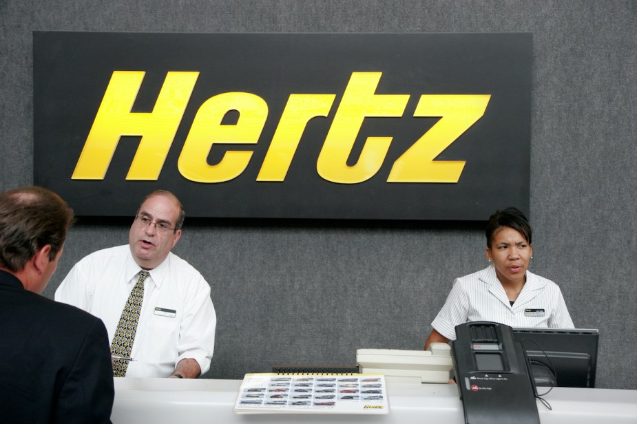 A couple of Hertz rental car agents help a customer.