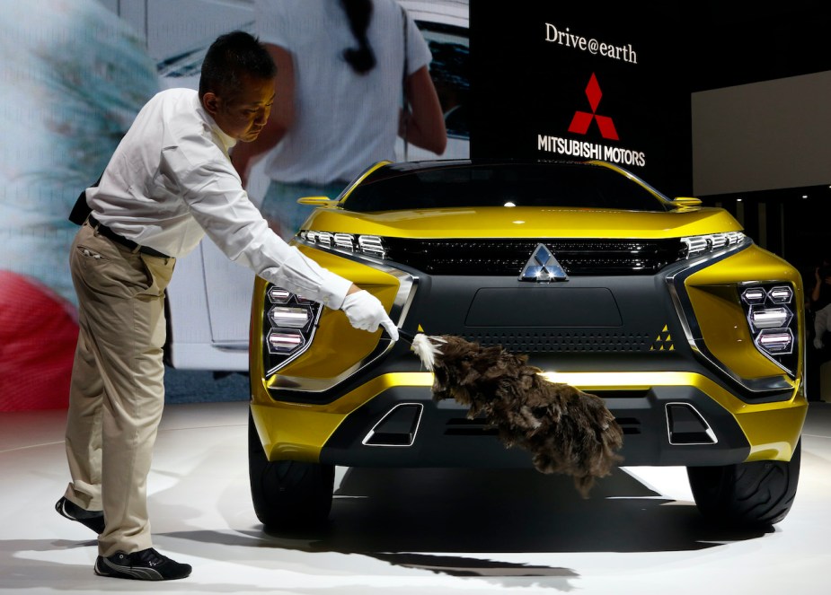 An attendant runs a feather duster over a Mitsubishi vehicle.
