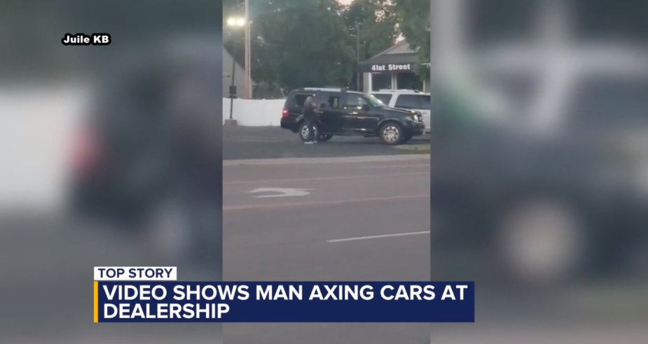 video screenshot of a man hitting new cars at a dealership with an axe.