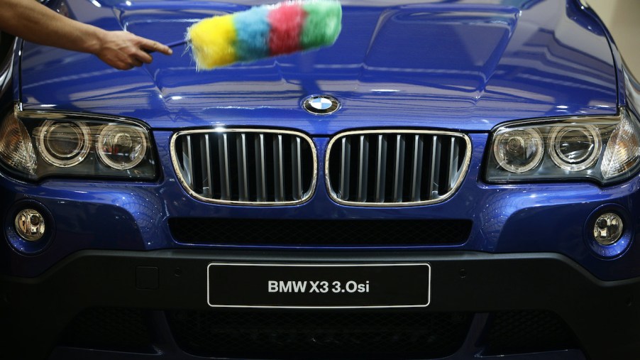 A worker cleans a BMW with a duster.