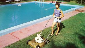A woman mowing her lawn and cutting grass by the pool