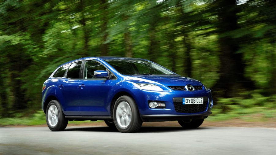 A blue 2008 Mazda CX-7 midsize crossover SUV driving on a forest road