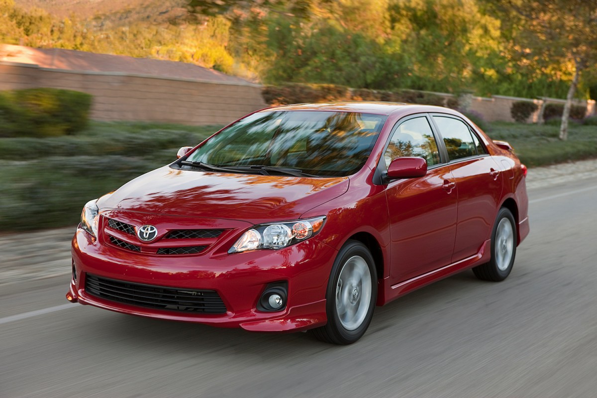 A red 2012 Toyota Corolla compact car driving down a street