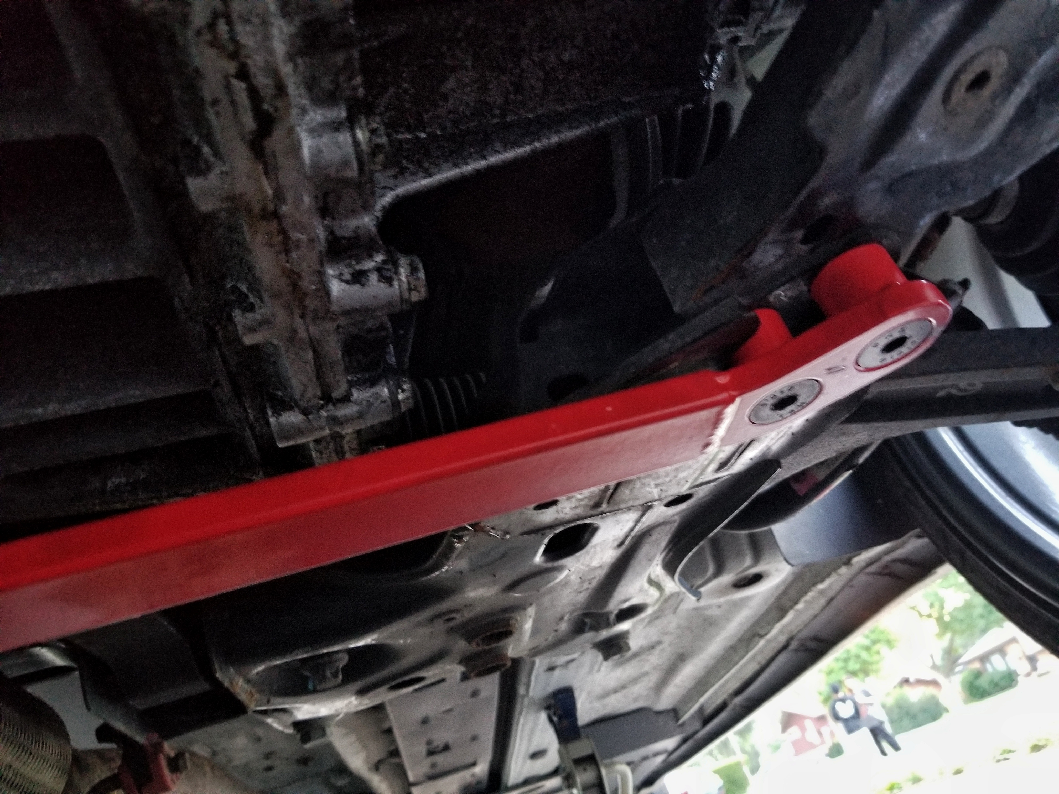 The driver's side underside view of a red Corsa Forza V1 lower subframe brace on a 2013 Fiat 500 Abarth