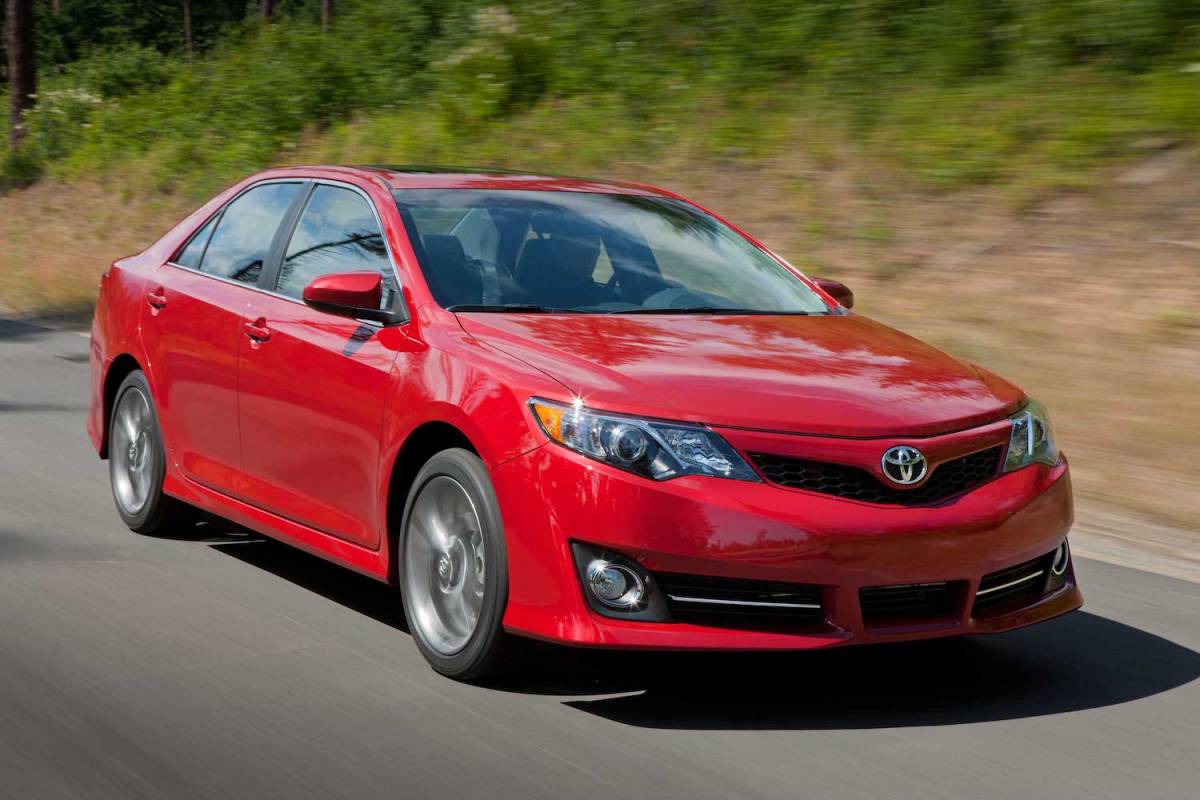 A red 2014 Toyota Camry drives