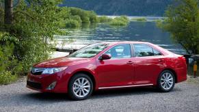 A red 2014 Toyota Camry XLE parked next to a pond