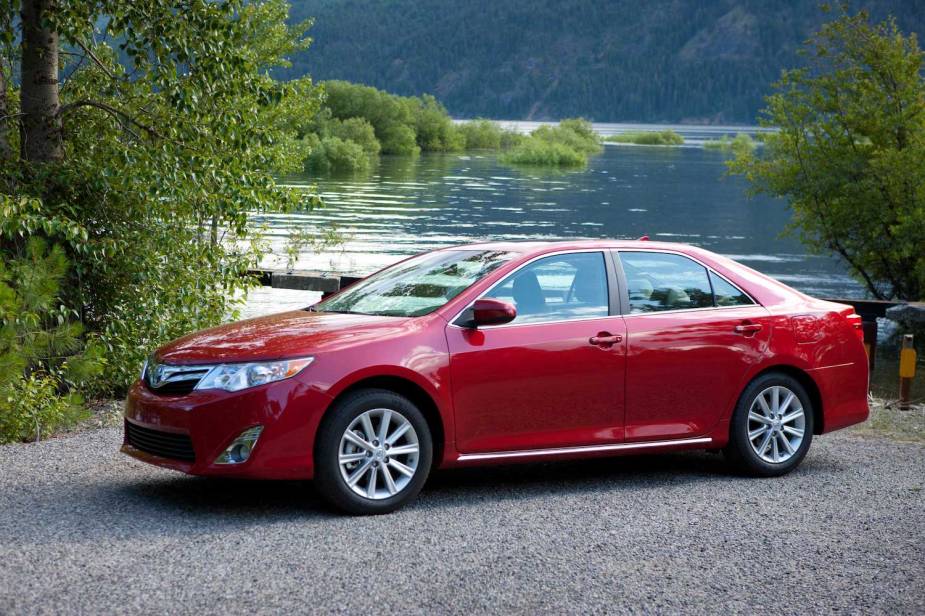 A red 2014 Toyota Camry XLE parked next to a pond