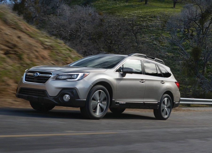 A silver 2018 Subaru Outback driving up a hill