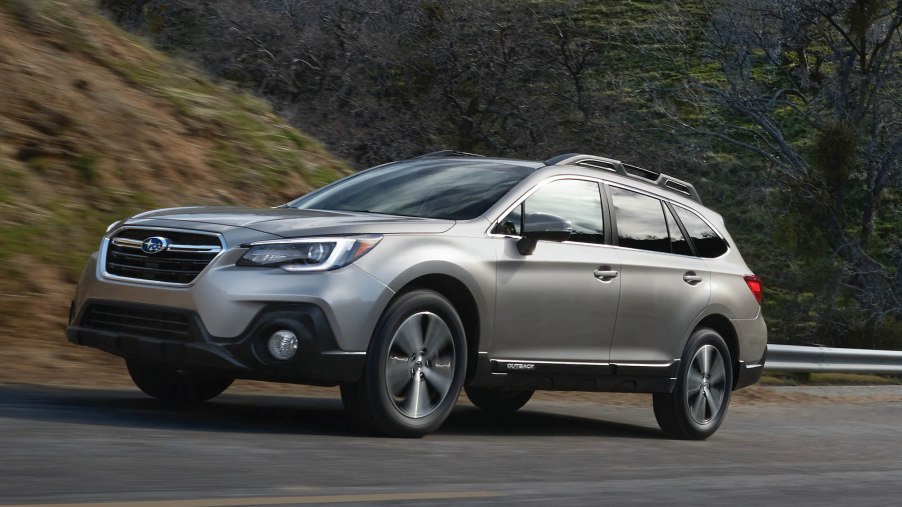 A silver 2018 Subaru Outback driving up a hill