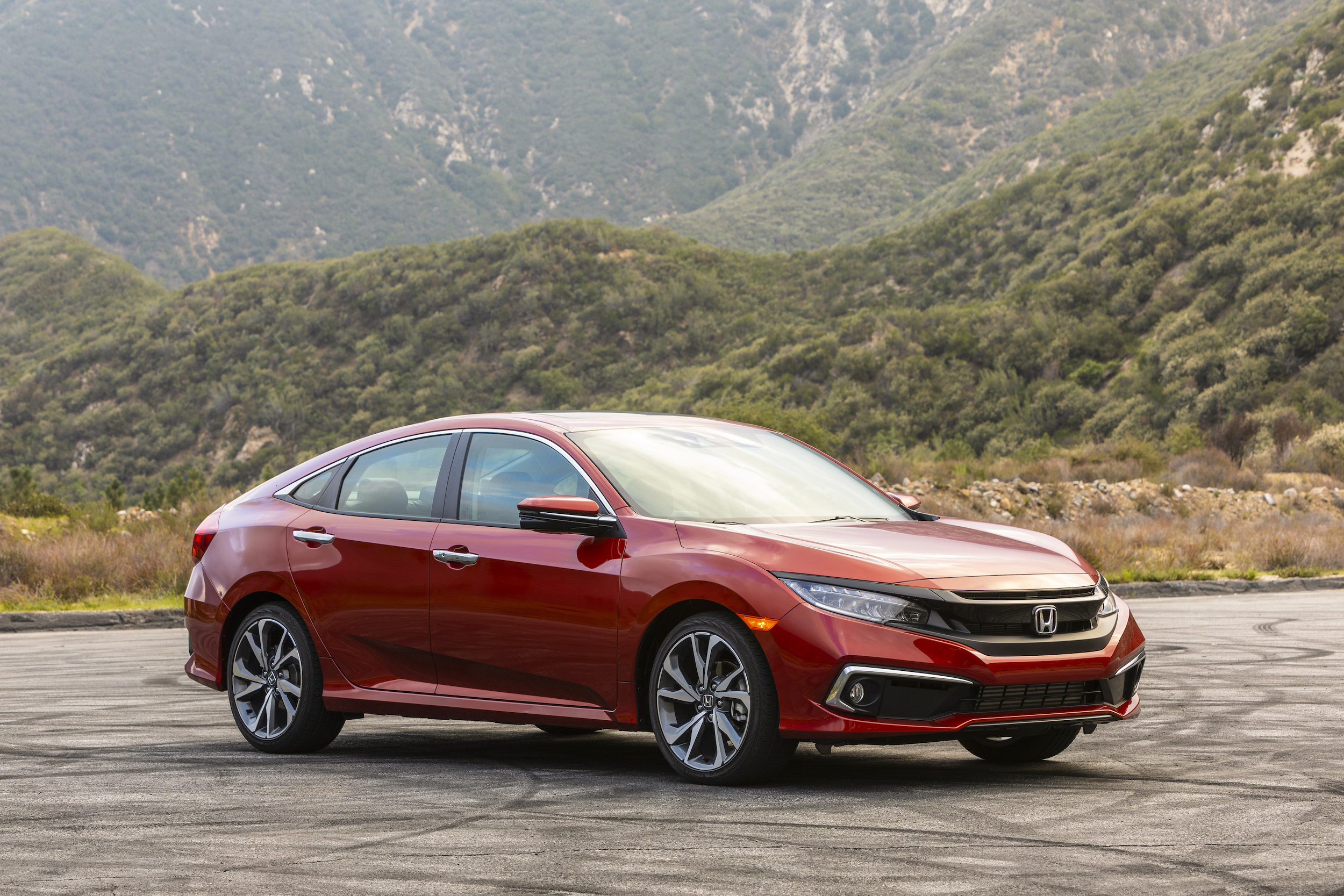 A red 2019 Honda Civic Sedan Touring parked in front of a mountain range