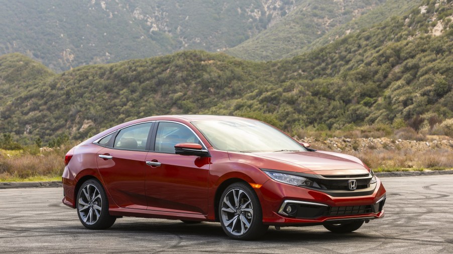 A red 2019 Honda Civic Sedan Touring parked in front of a mountain range