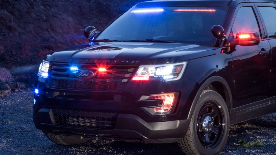 Promo shot of a black Ford SUV with red and blue police interceptor lights.