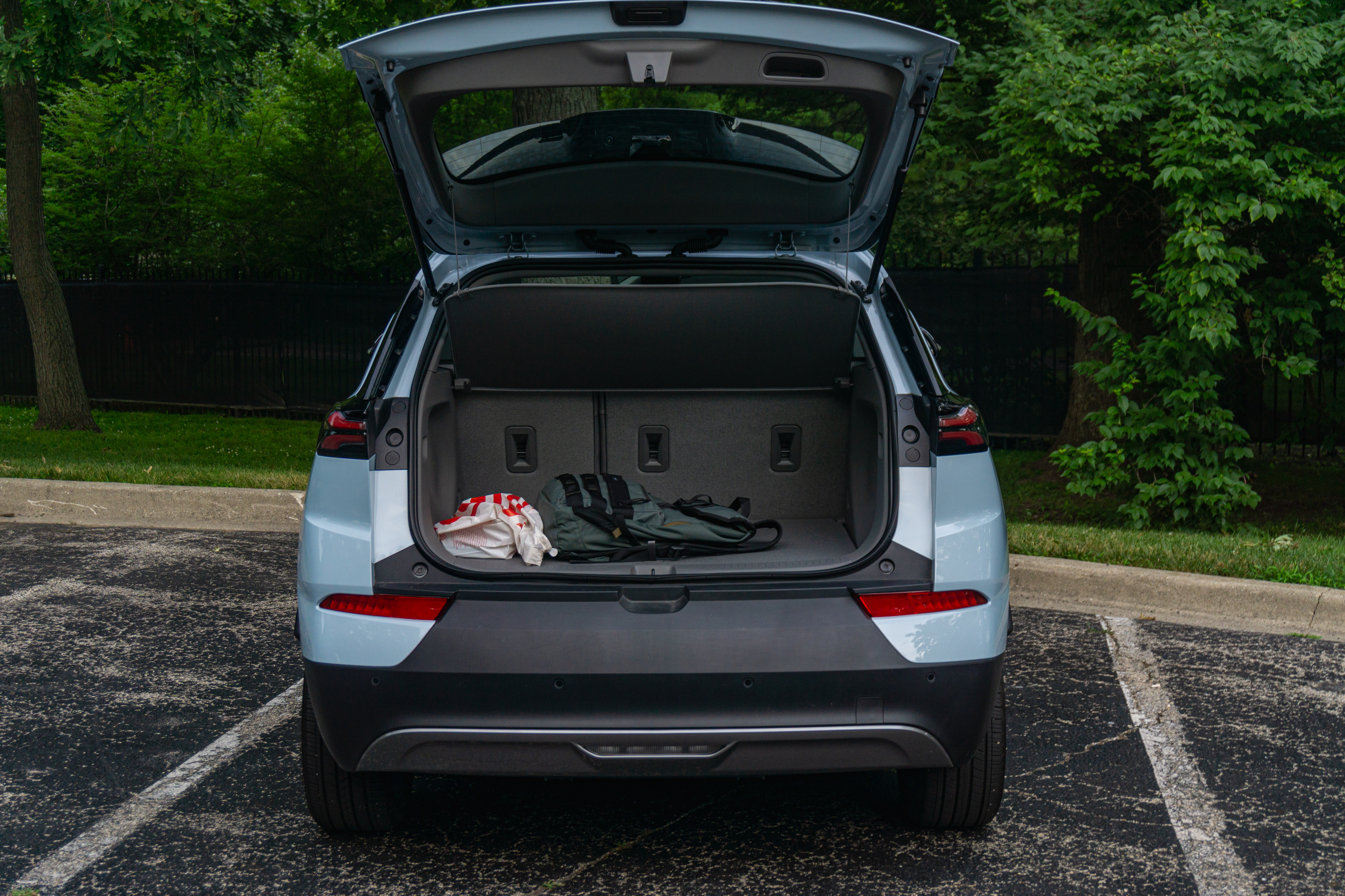 The open tailgate of a light-blue 2022 Chevrolet Bolt EUV Premier in a forest parking lot with bags in the rear cargo space